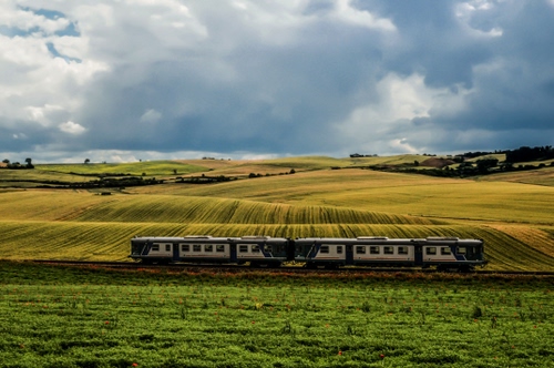 Immagine con treno, campi, verde, vagoni, nuvole, campagna, prati, colline, prato, nuvoloso, paesaggio, cielo, ferrovia