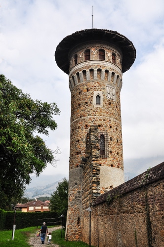 Immagine con torre, finestre, albero, persone, mura, nuvole, castello, cielo, strada, passanti, alberi