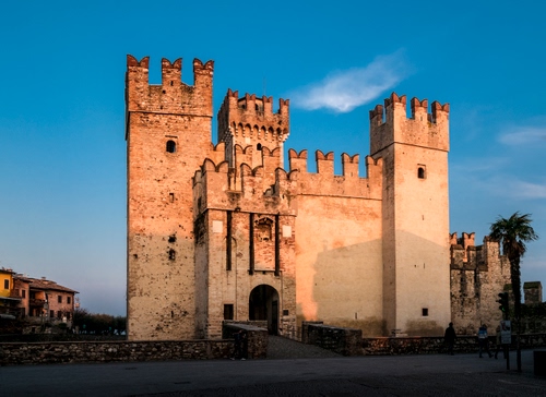 Immagine con castello, merli, torri, cielo, ponte, palma