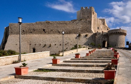 Immagine con castello, lampioni, vasi, torre, cielo, nuvole, azzurro, scale, torrione, gradini, rocca, blu, merli, mura, piante