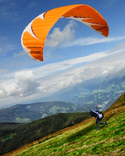 Immagine con montagna, parapendio, paracadute, montagne, volare, nuvole, sport, arancione, lancio, volo, paracadutista, prato, cielo, vela