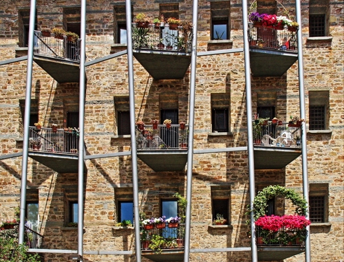 Immagine con balconi, finestre, fiori, palazzo, vasi, geometrie, facciata