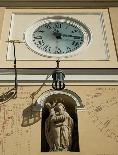 Immagine con orologio, statua, meridiana, lampione, ombra, madonna, lancette, ombre