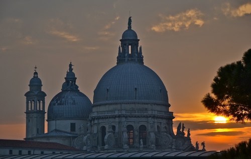 Immagine con tramonto, cupole, albero, chiesa, campanile, nuvole, cielo, statue, controluce, alberi, sole