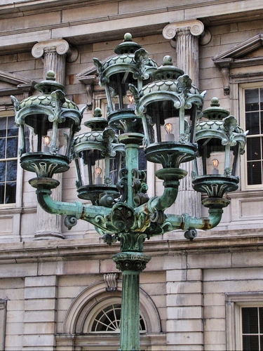Immagine con lampione, palazzo, finestre, lampadine, colonne, lampade, verde, luci, metallo, capitelli, braccia