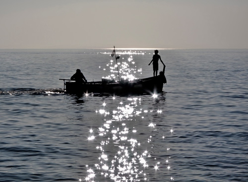 Immagine con barca, mare, controluce, acqua, silhouette, riflesso, timone, sole, persone, due, cielo, orizzonte, luccichio, pescatori, riflessi, scia