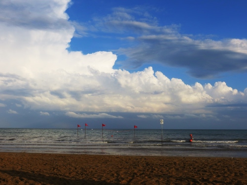 Immagine con mare, spiaggia, nuvole, bandiere, sabbia, bandierine, onde, cielo