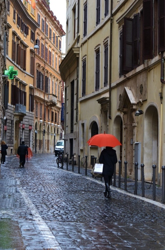 Immagine con strada, ombrello, pioggia, rosso, croce, finestre, passanti, farmacia, persone, porte, vicolo, verde, paletti, palazzi, bagnato, balconi, bicicletta, auto