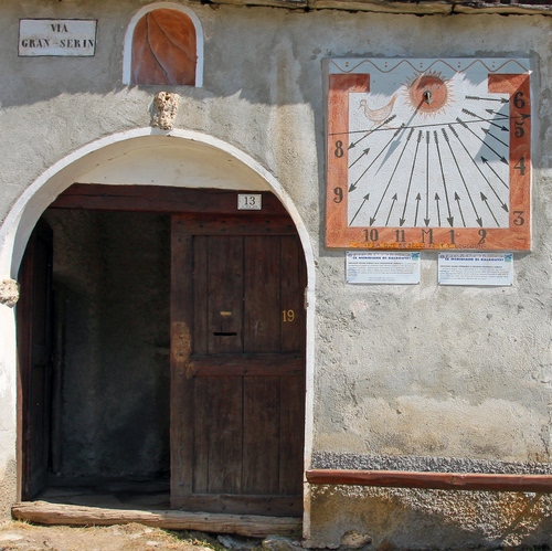 Immagine con meridiana, numeri, porta, portone, orologio, muro, legno, arco, civico, marrone, sole, ore, asta, ombra