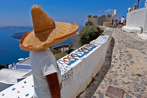Immagine con mare, cappello, bianco, strada, collane, persone, venditore, paglia, azzurro, cielo, sombrero, piante, uomo, alberi, verde, muretto, muro, vicolo, panorama, maglietta