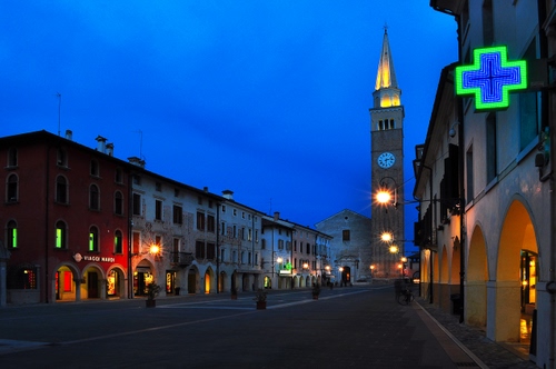 Immagine con croce, campanile, orologio, chiesa, case, portici, notte, piazza, farmacia, luci, strada, blu, finestre, notturno, via, scorcio, archi, insegna