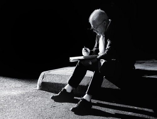 Immagine con uomo, occhiali, penna, scarpe, ombre, bianconero, quaderno, ombra, nero, seduto, orologio, bianco, appunti, scrive, luce, scrittura, persona, blocco