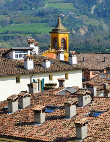 Immagine con campanile, comignoli, tetti, tegole, verde, coppi, abbaini, abbaino, finestre, camini, giallo, montagna, lucernari, prati, case, alberi