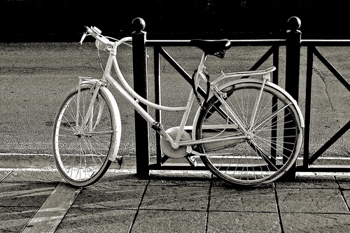 Immagine con bicicletta, ruote, bianconero, strada, ringhiera, bianco, manubrio, sellino, pedali, sella, raggi, marciapiede, ferro