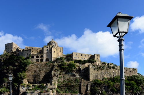 Immagine con archi, nuvole, lampione, mura, cielo, lampioni, cupola, alberi, azzurro, collina, finestre, castello, bianco, fortezza, antico, verde, case, borgo