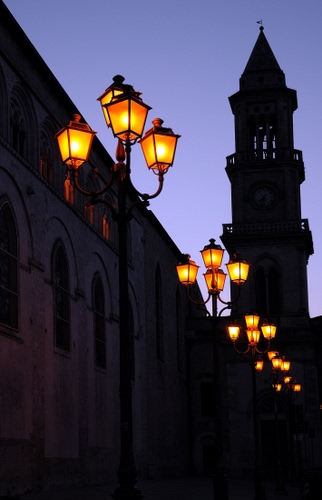 Immagine con lampioni, campanile, luci, sera, finestre, cielo, accesi, controluce, torre