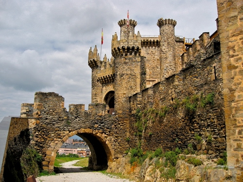 Immagine con castello, torri, bandiere, merli, mura, arco, ponte, strada, nuvole, pietra, torre