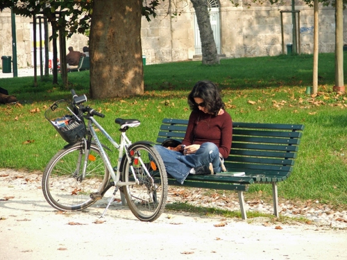 Immagine con panchina, bicicletta, donna, prato, leggere, verde, alberi, seduta, tronco, ragazza