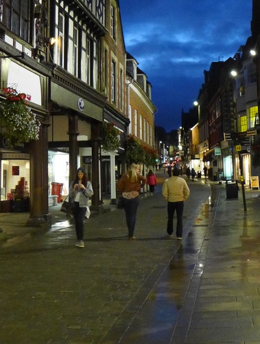 Immagine con strada, nuvole, persone, luci, lampioni, pioggia, cielo, notturno, vetrine, via, sera, finestre, notte, bagnato, passanti, portici, palazzi, negozi, riflessi, case