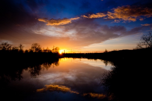Immagine con tramonto, nuvole, fiume, sole, riflessi, acqua, riflesso, stagno, paesaggio, cielo, alberi