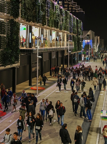 Immagine con strada, persone, notte, verde, passanti, gente, passeggio, palazzi, lampioni, sera, notturno, vetrine, giovani, luci, expo, case, ragazzi, folla