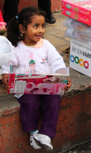 Immagine con bambina, giocattolo, viola, scarpe, sorriso, bianco, bambola, seduta, scatola, codini