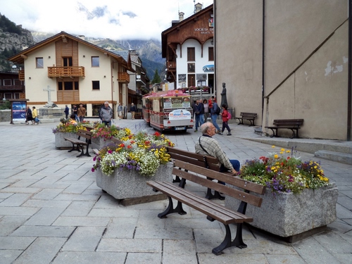 Immagine con panchine, fiori, piazza, vasi, case, persone, panchina, fioriere