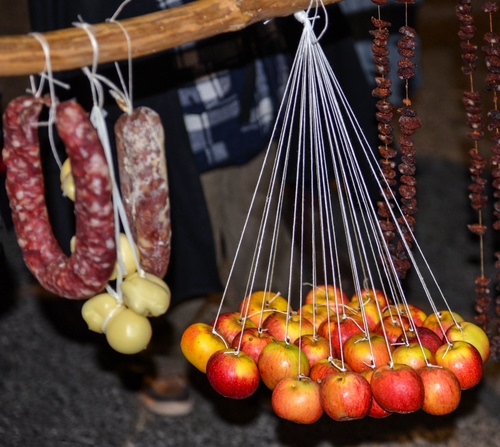 Immagine con mele, salame, salami, frutta, fili, formaggio, salsiccia, formaggi, appese, appesi, cibo