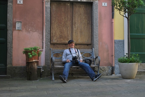 Immagine con panchina, fotografo, vasi, piante, uomo, verde, porte, numeri, riposo, seduto, finestra, anziano, porta, cappello, citofono