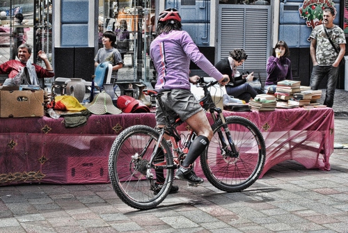 Immagine con bicicletta, libri, casco, ciclista, persone, ruote, cappelli, mercatino, mercato, banco, rosso, raggi, bancarella, vintage