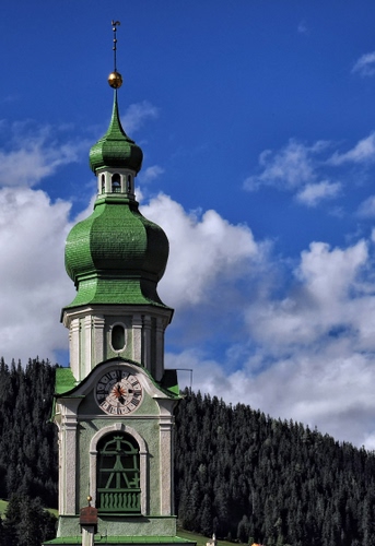 Immagine con campanile, orologio, verde, montagna, nuvole, cielo, alberi, pineta, cupola, guglia