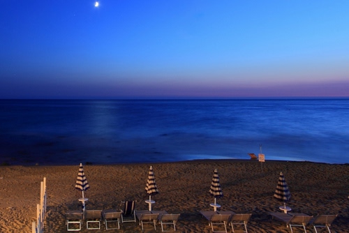 Immagine con mare, spiaggia, ombrelloni, luna, blu, sera, sdraio