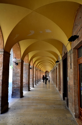 Immagine con archi, giallo, colonne, portico, portici, prospettiva, persone, gente, porticato, lampione, volte