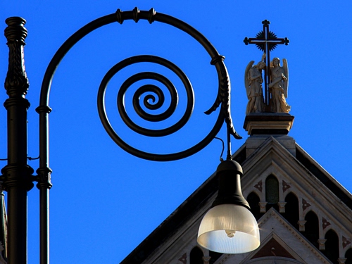 Immagine con lampione, spirale, croce, angeli, cielo, chiesa, azzurro, statue, palo, ferro, lampada, blu