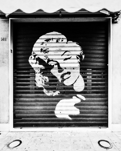 Immagine con donna, serranda, negozio, saracinesca, bianconero, nero, bocca, bianco, volto, attrice, tenda, capelli, marciapiede, occhi, murale, murales, marilyn, viso, ritratto, naso