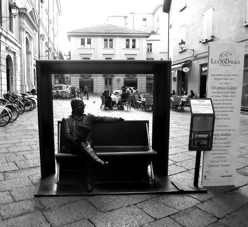 Immagine con panchina, biciclette, piazza, statua, bianconero, tavolini, finestre, cartello, lampione, strada, monumento