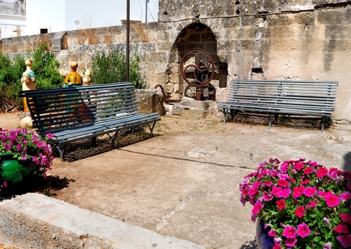 Immagine con panchine, fiori, muro, statue, fucsia, ruota, fontana
