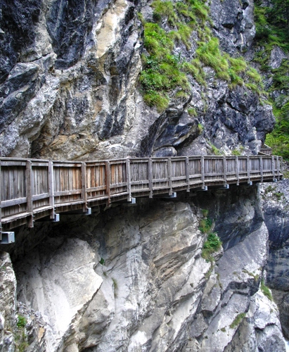 Immagine con roccia, legno, verde, montagna, staccionata, ponte, passerella, sentiero, erba, rocce, grigio, steccato, piante, cespugli, muschio, parete