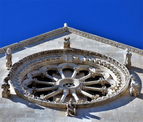 Immagine con rosone, cielo, chiesa, cerchio, azzurro, statue, colonne, facciata, raggi, decorazioni, tondo, dettaglio, archi, capitelli, sculture, blu