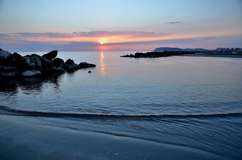Immagine con tramonto, mare, scogli, acqua, cielo, sole, nuvole, alba, azzurro, onda, spiaggia, scogliera, riflesso, riflessi, frangiflutti, orizzonte, onde