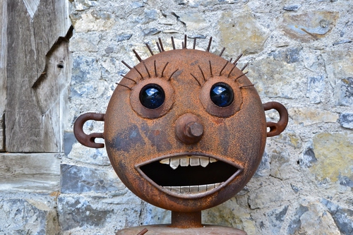 Immagine con denti, bocca, occhi, ruggine, muro, naso, ferro, pupazzo, orecchie, scultura, faccia, ciglia, capelli, porta, metallo