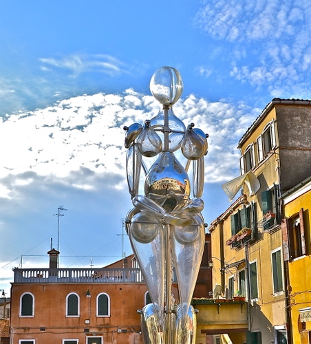 Immagine con nuvole, cielo, finestre, vetro, balaustra, case, azzurro, scultura, statua, riflessi, trasparente, palazzi, donna, giallo, arte, vasi, plastica, riflesso